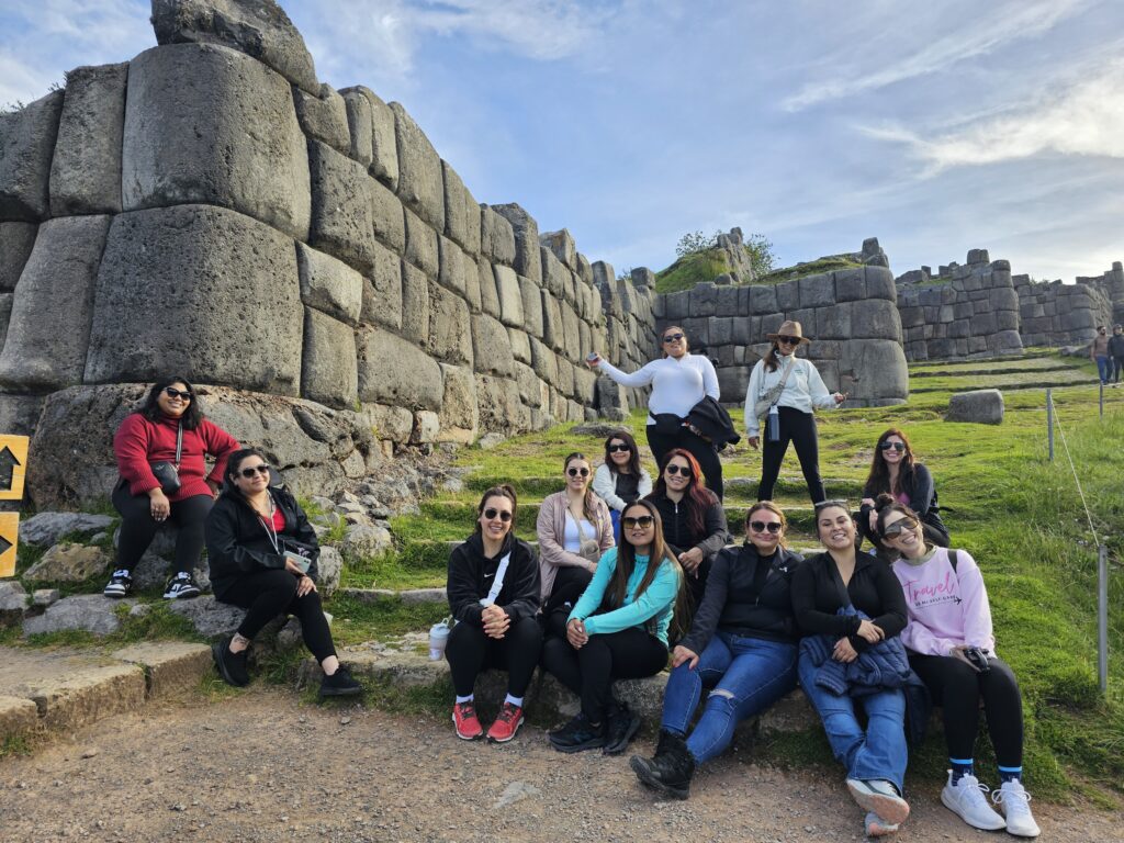 Turistas explorando las murallas de piedra de Sacsayhuamán en el City Tour.